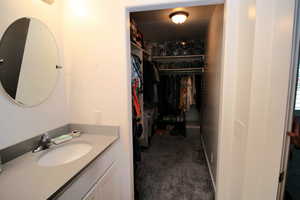 Bathroom with a walk in closet and vanity