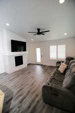 Living room featuring baseboards, a fireplace, wood finished floors, and a ceiling fan