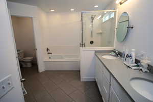 Bathroom with a stall shower, a bath, toilet, and a sink