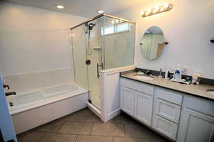 Bathroom featuring tile patterned flooring, a shower stall, a sink, double vanity, and a bath