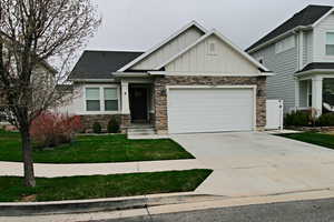 Craftsman-style house with stone siding, board and batten siding, concrete driveway, and an attached garage