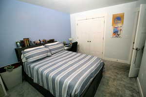 Carpeted bedroom with a closet and baseboards