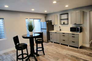 Kitchen featuring a sink, stainless steel appliances, gray cabinetry, and light wood-type flooring