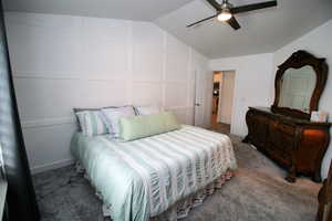 Bedroom with carpet flooring, lofted ceiling, ceiling fan, and a decorative wall