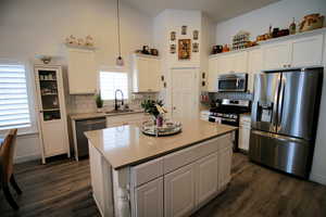 Kitchen featuring a sink, appliances with stainless steel finishes, dark wood finished floors, white cabinets, and decorative backsplash