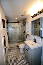 Full bathroom featuring a stall shower, visible vents, toilet, and vanity