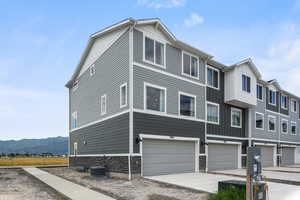View of front facade featuring driveway, stone siding, an attached garage, board and batten siding, and a mountain view