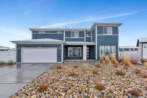 View of front of house with concrete driveway, fence, and an attached garage