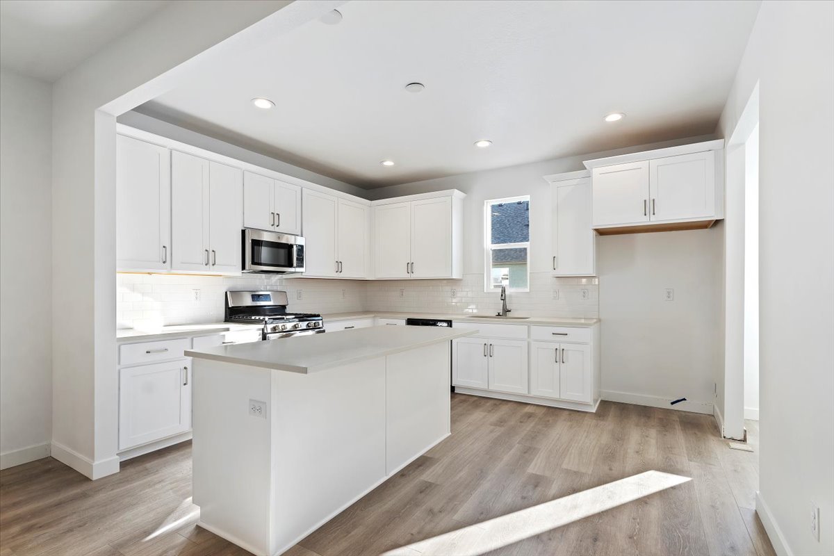 Kitchen featuring a sink, tasteful backsplash, appliances with stainless steel finishes, and light wood-type flooring