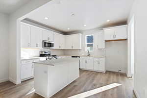 Kitchen featuring a sink, tasteful backsplash, appliances with stainless steel finishes, and light wood-type flooring
