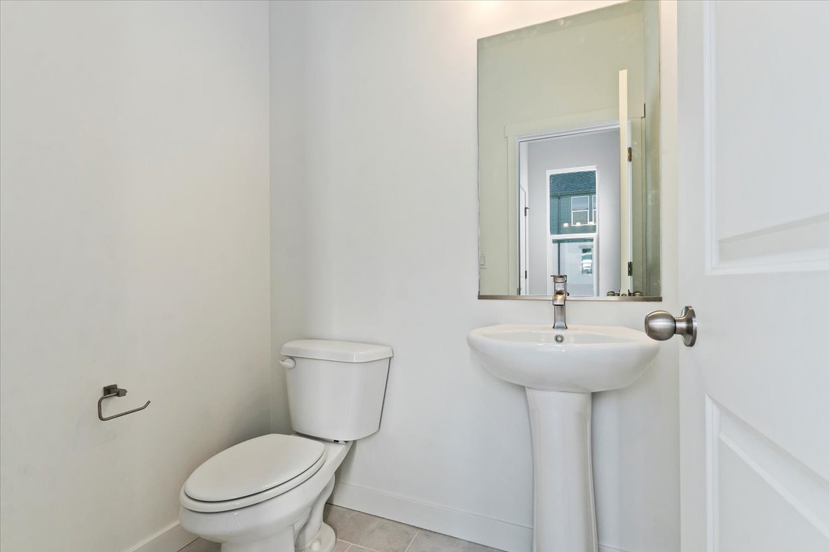 Half bath featuring baseboards, toilet, and tile patterned floors