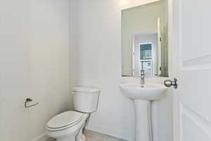 Half bath featuring baseboards, toilet, and tile patterned floors