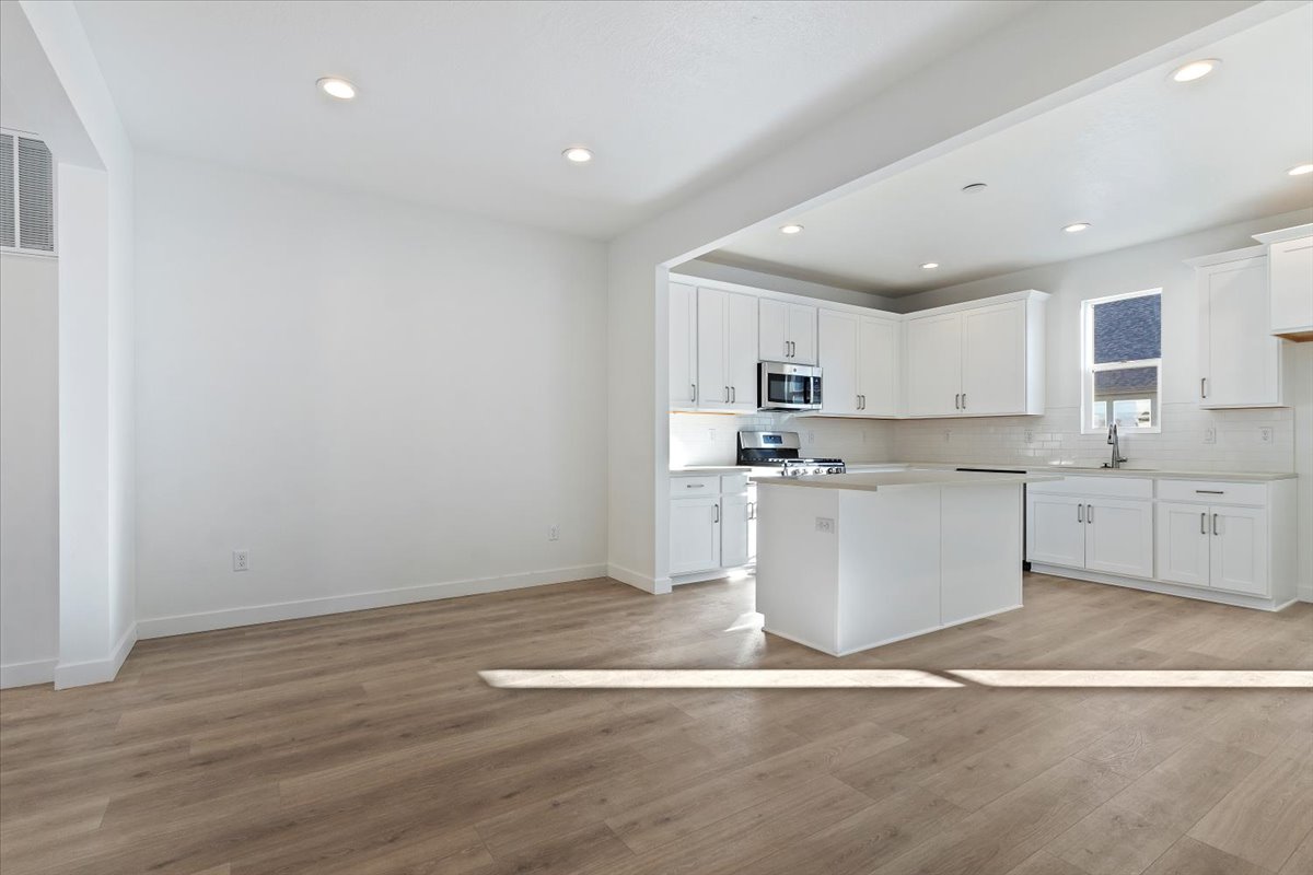 Kitchen featuring light countertops, baseboards, appliances with stainless steel finishes, light wood-type flooring, and backsplash