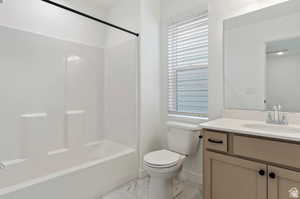 Full bath with marble finish floor, toilet, vanity, and shower / washtub combination