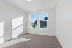 Carpeted spare room with baseboards and visible vents