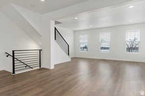 Unfurnished living room featuring baseboards, wood finished floors, recessed lighting, and a healthy amount of sunlight