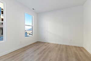 Spare room with baseboards, visible vents, and light wood-style floors