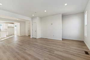 Unfurnished living room featuring light wood-style flooring, visible vents, recessed lighting, and plenty of natural light