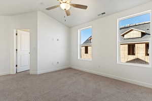 Empty room featuring lofted ceiling, baseboards, carpet floors, ceiling fan, and visible vents