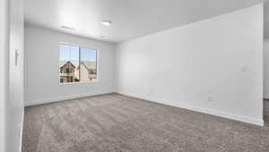 Carpeted empty room with baseboards, a textured ceiling, and visible vents