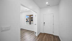 Foyer entrance with baseboards, visible vents, and wood finished floors