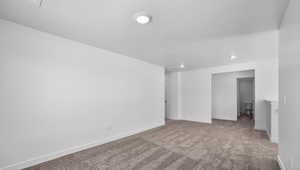 Spare room featuring carpet floors, baseboards, and a textured ceiling