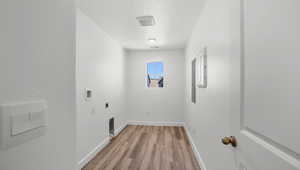 Clothes washing area with a textured ceiling, electric dryer hookup, laundry area, light wood-style floors, and hookup for a washing machine