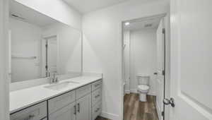 Full bath featuring visible vents, baseboards, toilet, wood finished floors, and vanity