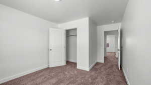 Unfurnished bedroom with baseboards, a closet, dark carpet, and a textured ceiling