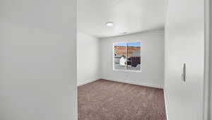 Spare room featuring baseboards, carpet floors, a textured ceiling, and visible vents