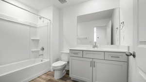 Bathroom with vanity, toilet, visible vents, shower / bathtub combination, and wood finished floors