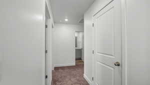 Hall with baseboards, visible vents, and carpet floors