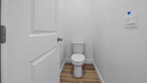 Bathroom with baseboards, wood finished floors, and toilet