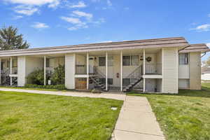 View of front of home featuring a porch, mansard roof, a front lawn, and stairs