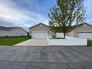 View of back of house featuring concrete driveway, stucco siding, a fenced backyard, large side yard, and 2 car garage