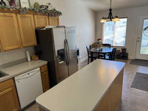 Kitchen featuring light countertops, a chandelier, fridge with ice dispenser, pendant lighting, and white dishwasher