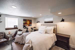 Bedroom featuring a textured ceiling, baseboards, and recessed lighting
