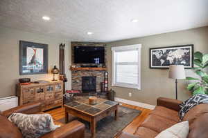 Living area with recessed lighting, baseboards, a textured ceiling, and wood finished floors