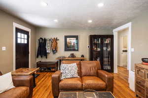 Living area with a textured ceiling, wood finished floors, and recessed lighting