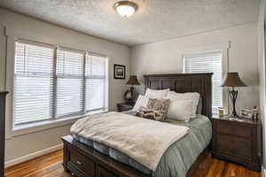 Bedroom featuring a textured ceiling, wood finished floors, and multiple windows