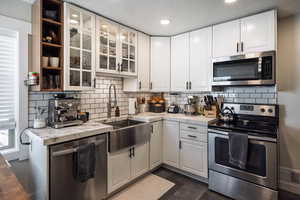 Kitchen featuring appliances with stainless steel finishes, a sink, light countertops, and white cabinetry