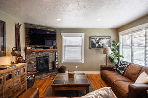 Living area with a wealth of natural light, a textured ceiling, and wood finished floors