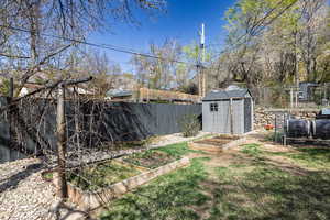 View of yard with a garden, a fenced backyard, a storage unit, and an outdoor structure