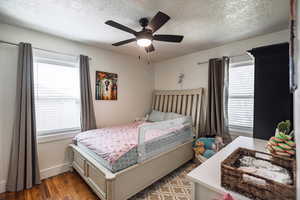 Bedroom featuring a textured ceiling, wood finished floors, and ceiling fan