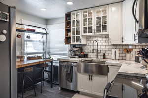 Kitchen featuring white cabinets, a textured ceiling, decorative backsplash, and appliances with stainless steel finishes