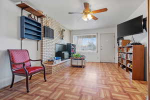 Sitting room featuring a wood stove and a ceiling fan