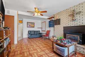 Living room featuring a fireplace, visible vents, and ceiling fan