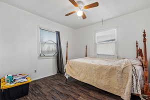 Bedroom featuring multiple windows, wood finished floors, baseboards, and a ceiling fan