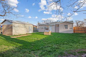 Rear view of property with solar panels, fence, a lawn, and an outdoor structure