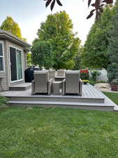 Wooden deck with grilling area, an outdoor living space, and a lawn